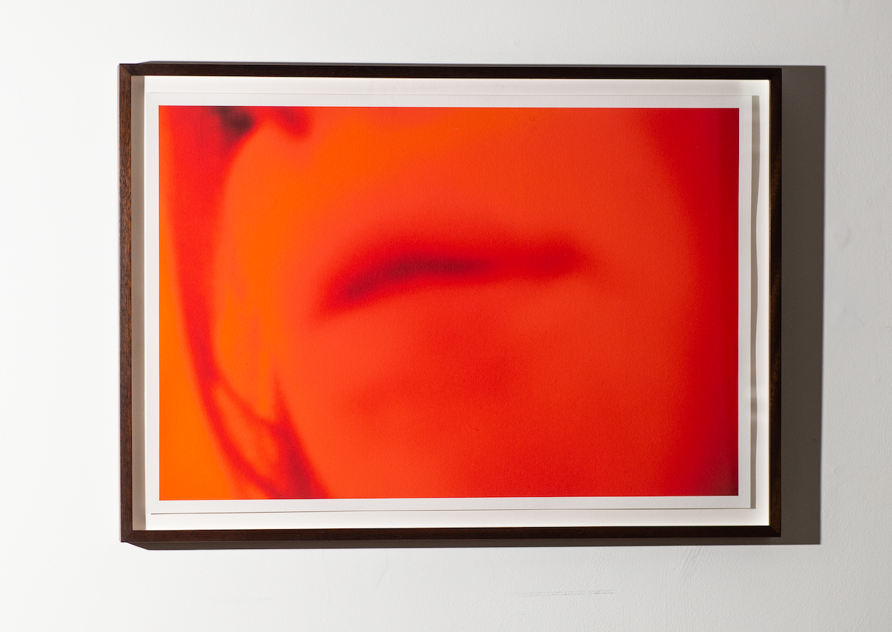 Framed artwork with a close-up of a person's face on a white wall