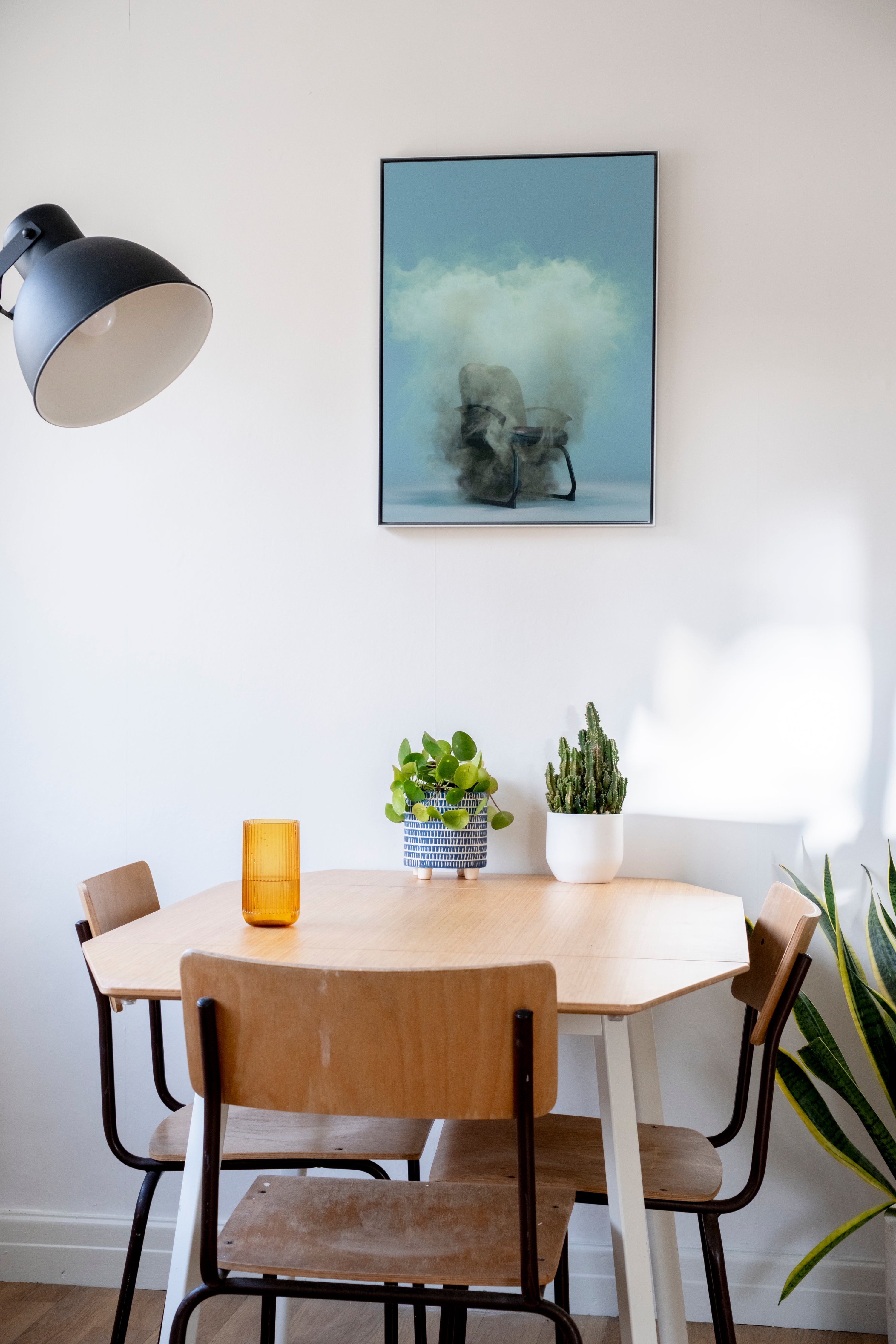 Dining area with a round table, chairs, and wall art in a home setting.
