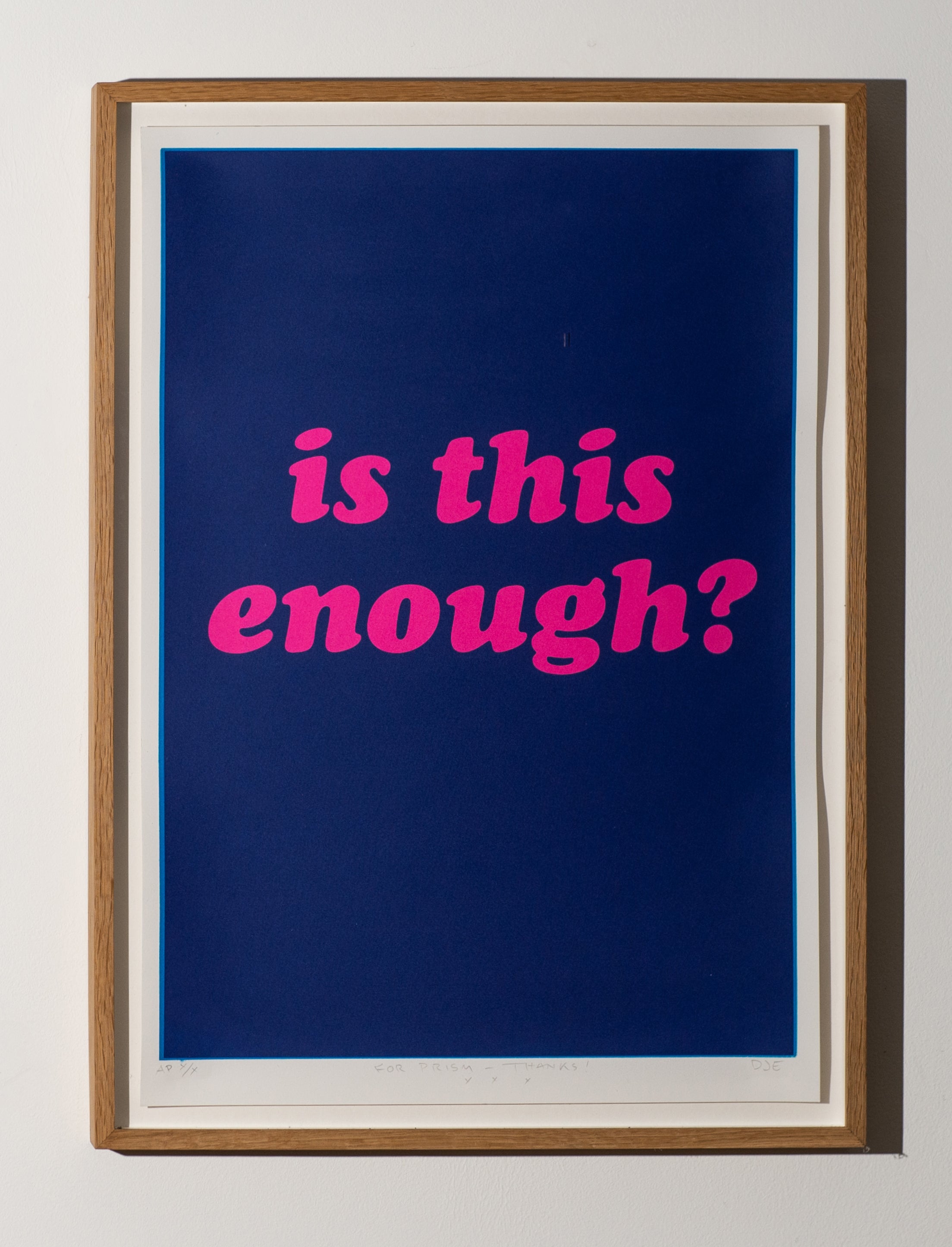 Framed artwork with pink text 'is this enough?' on a blue background