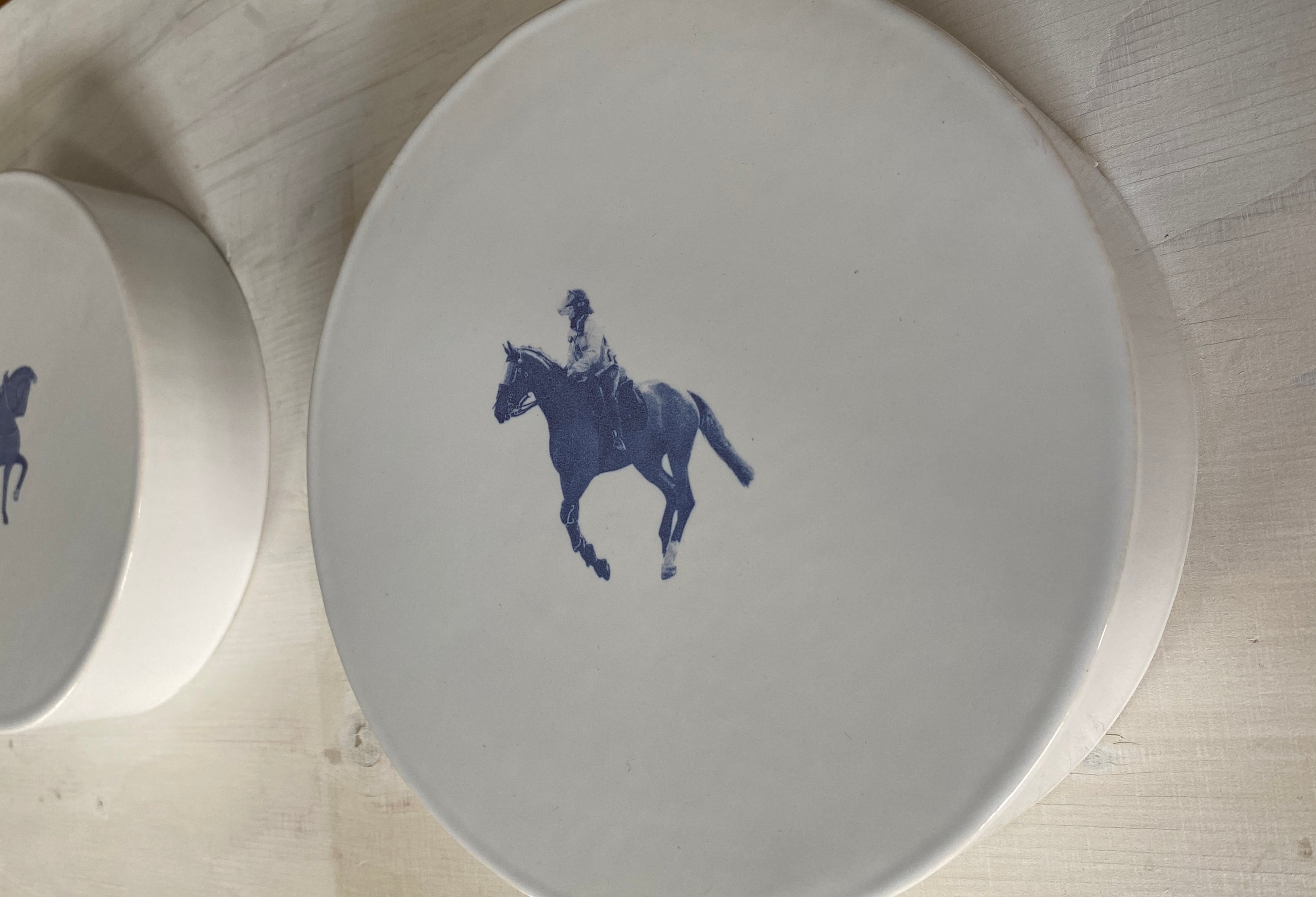 White plate with blue horse and rider design on a wooden surface
