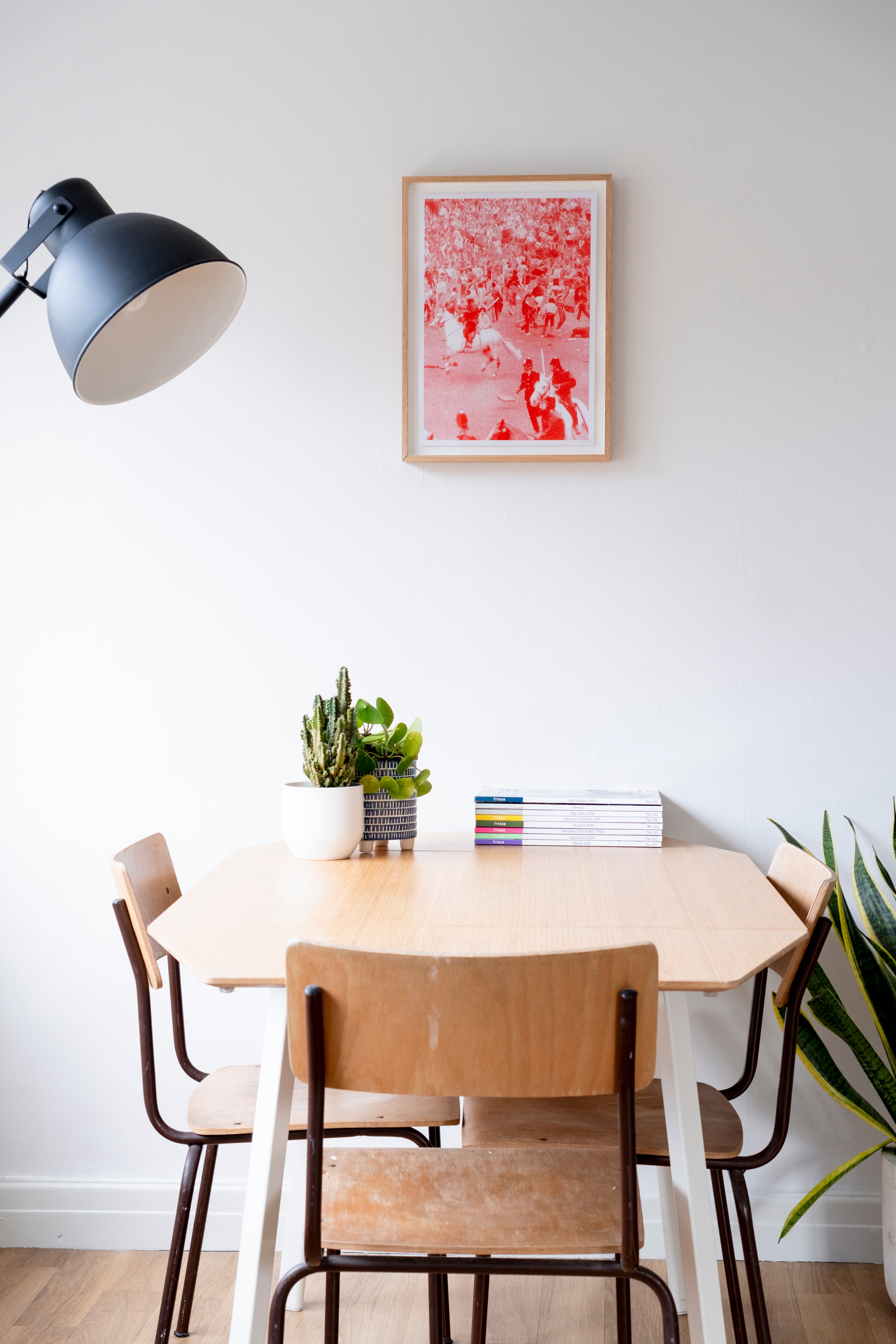 Dining area with a round table and chairs, a lamp, and a red abstract painting on the wall.